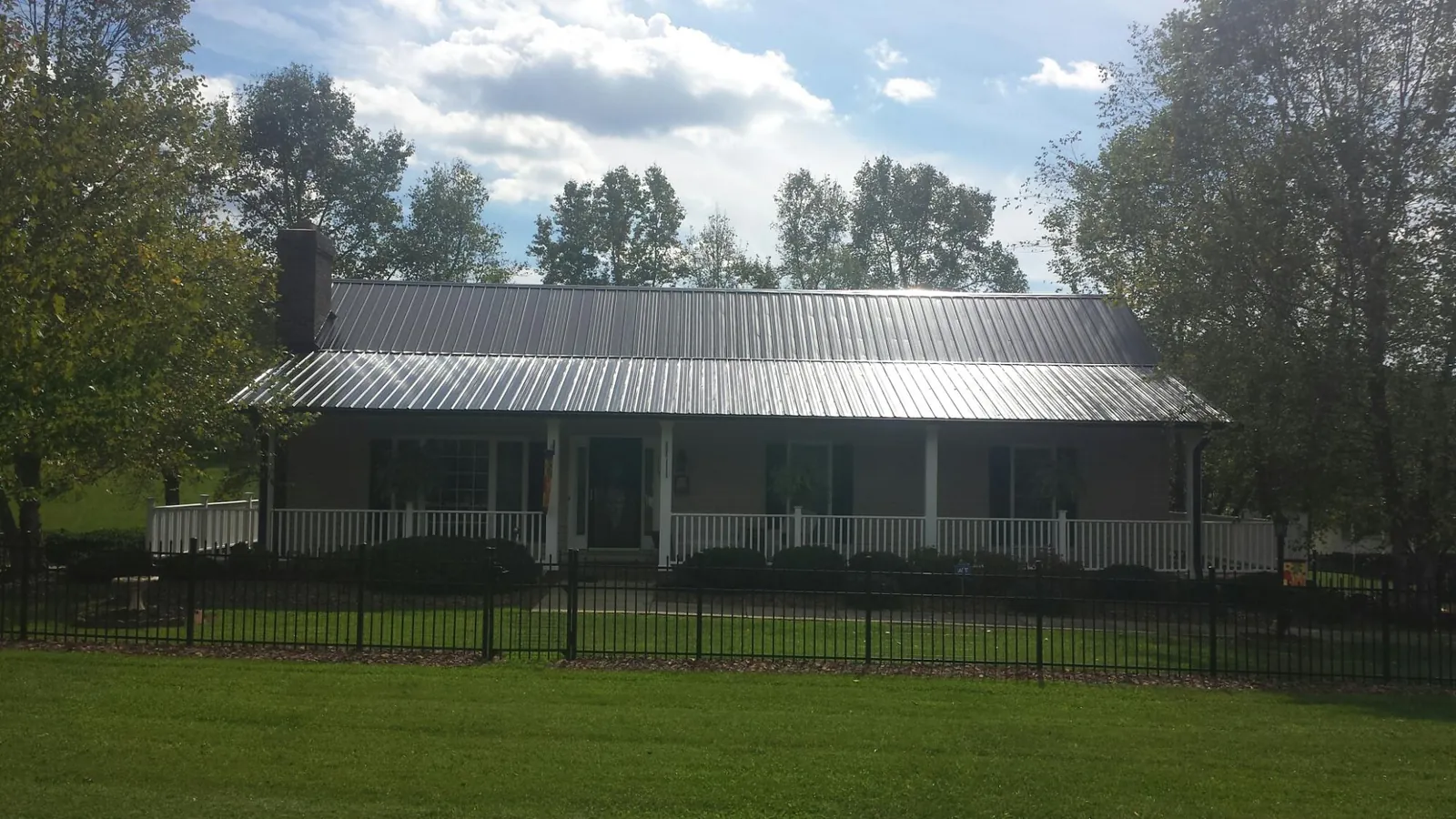 Gray metal roof on a brick ranch with a full width front porch — Gutter Guard Installation work by our crew in Townsend